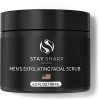 A sleek black container of Keep Sharp's Exfoliating Face Scrub, surrounded by fresh aloe leaves and witch hazel branches, against a backdrop of clean, glowing skin.
